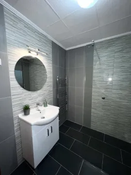 Moderno kupatilo sa tuš kabinom, bijelim lavaboom i okruglim ogledalom. - image 14