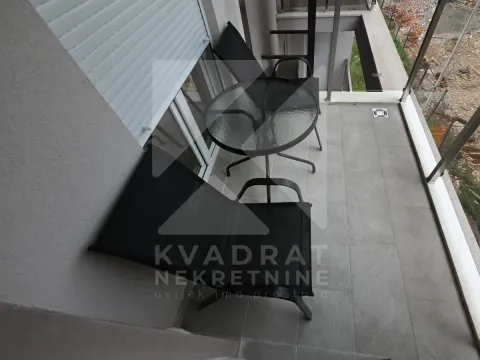 Small furnished balcony with a glass table and black chairs. - image 4