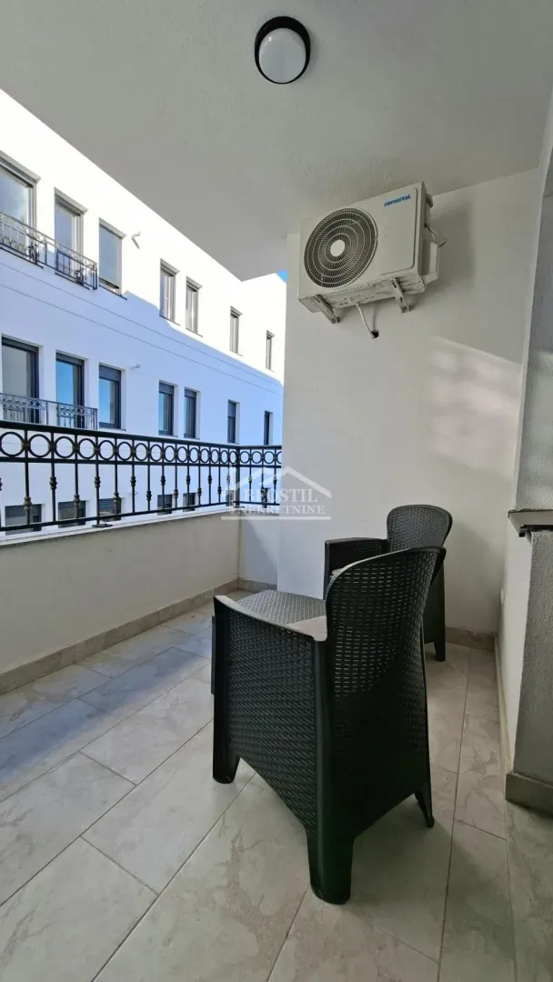 Manji natkriveni balkon sa garniturom za sedenje i klimom na zidu.