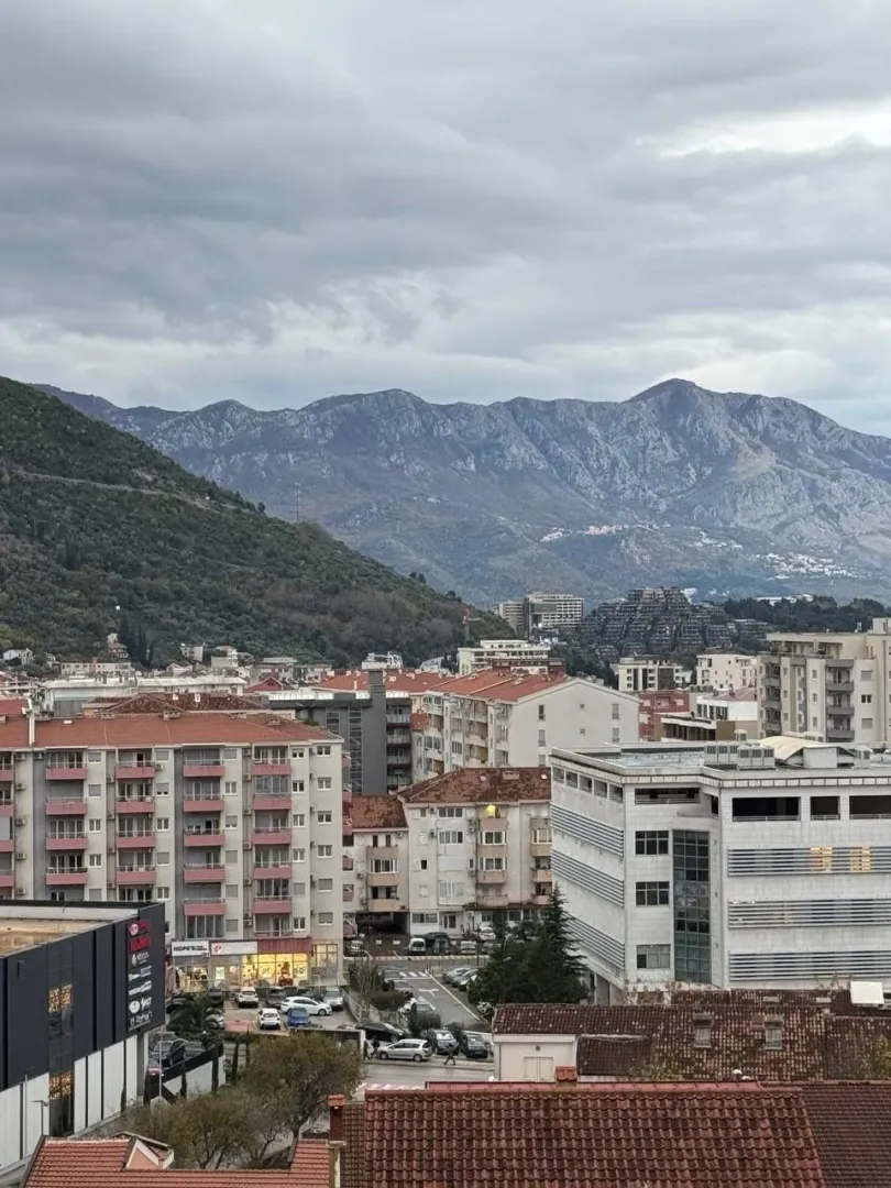 Pogled sa prozora na grad i planine u pozadini.