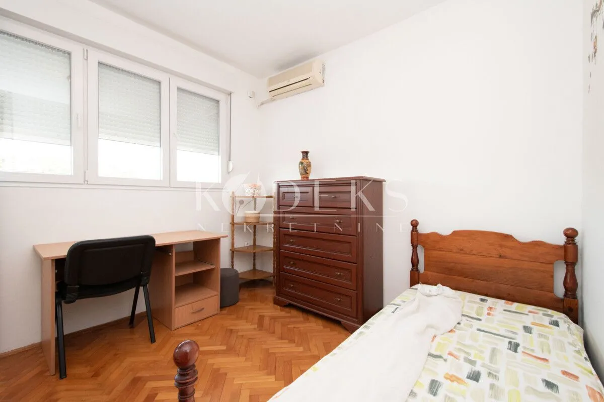 Bedroom with a bed, desk, and wooden chest of drawers.