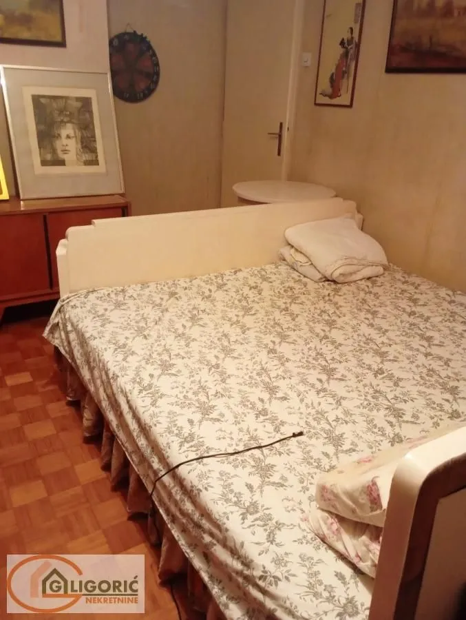 Nameštena spavaća soba sa bračnim krevetom i slikama na zidu.