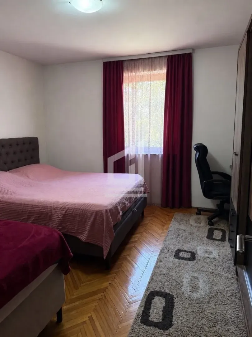 Namještena spavaća soba sa bračnim krevetom, radnim stolom i prozorom.