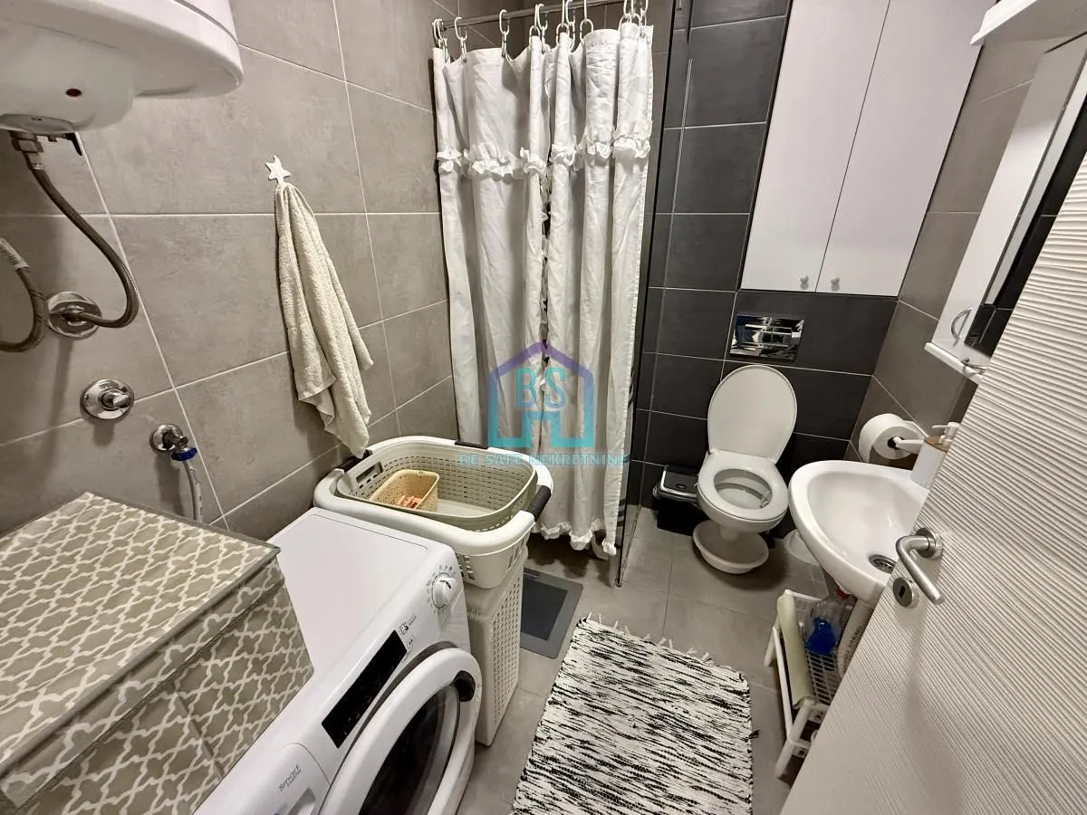 Manje kupatilo sa tuš kabinom, wc šoljom, umivaonikom i mašinom za veš.