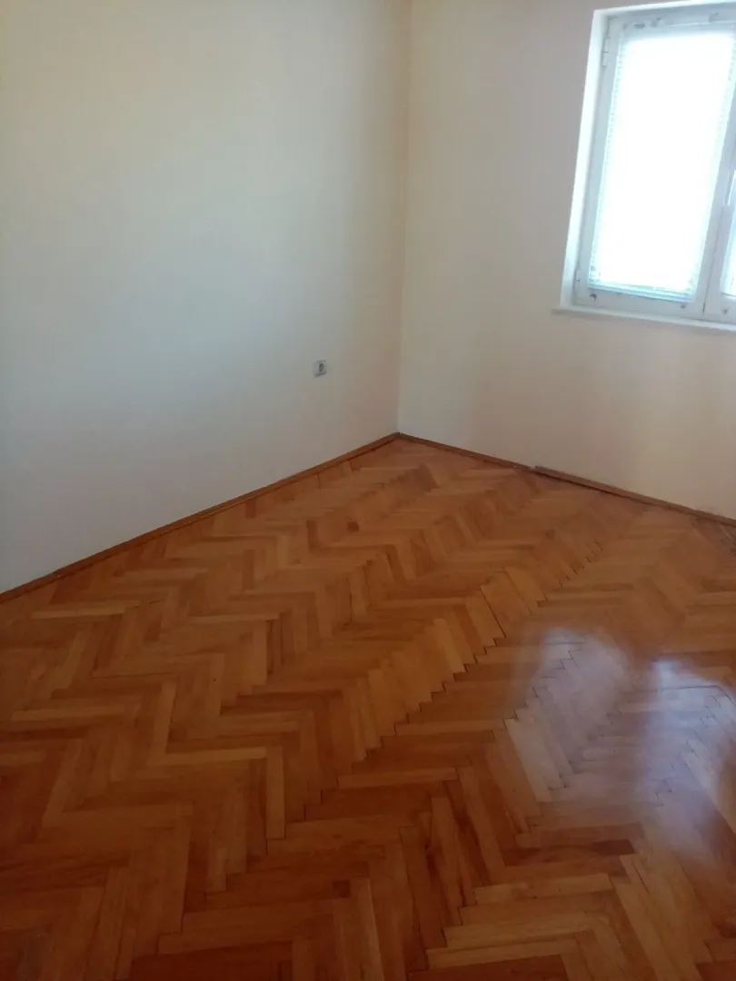 An empty room featuring parquet flooring and a window.