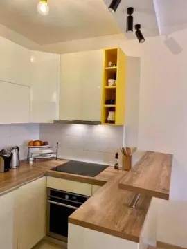 Modern kitchen with white cabinets, wooden countertops, and a breakfast bar. - image 4