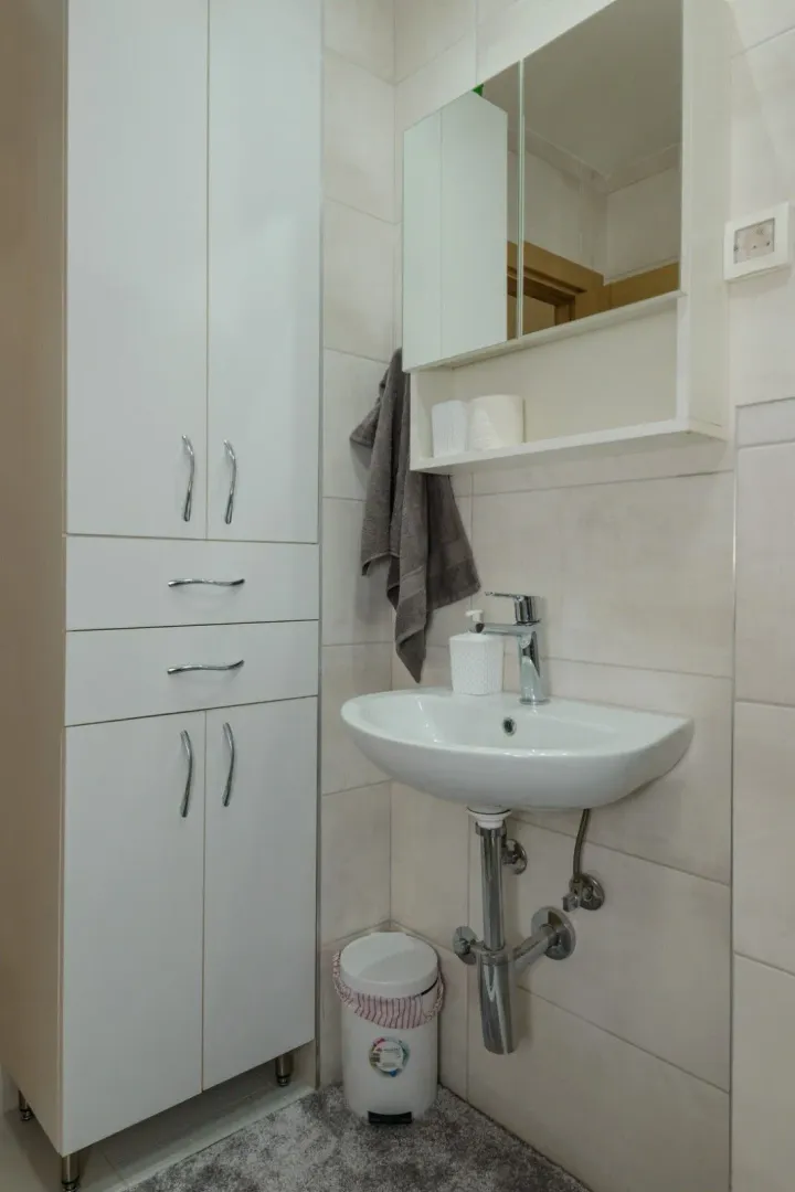 Svijetlo kupatilo sa bijelim ormarićem i umivaonikom.