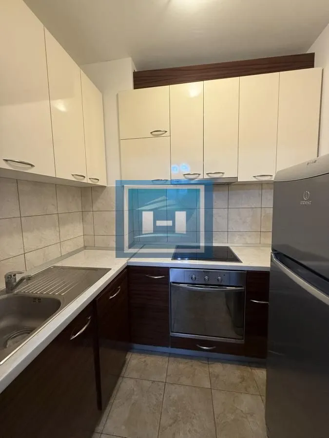 Small kitchen with white cabinets, built-in oven, and a refrigerator.