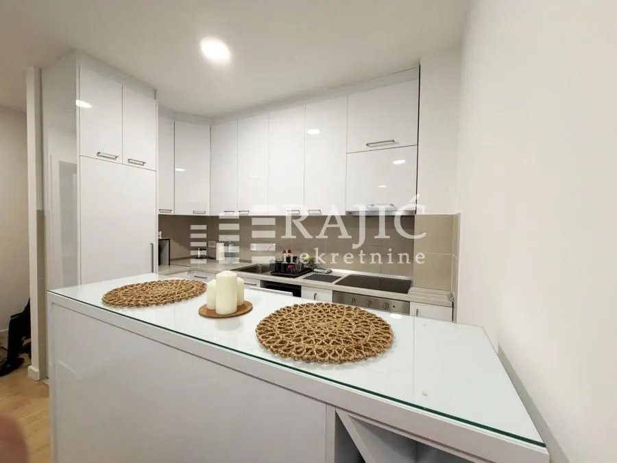 Modern white kitchen with a bar counter and built-in appliances.