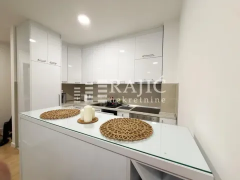 Modern white kitchen with a bar counter and built-in appliances. - image 5