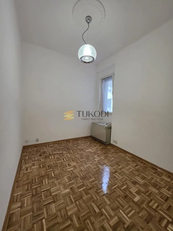 Empty room with parquet flooring and a ceiling light.