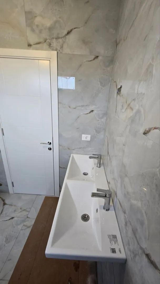 Moderne dvostruke umivaonike sa mermernim pločicama u kupatilu.