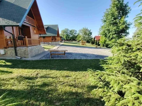 Pogled na drvene vikendice i uređeno dvorište sa zelenilom. - image 18