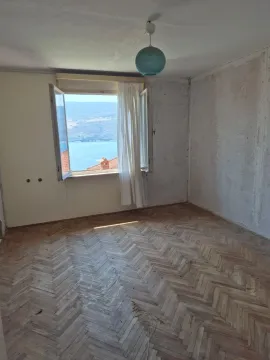 Prazna soba sa drvenim parketom i pogledom na more kroz prozor. - image 2
