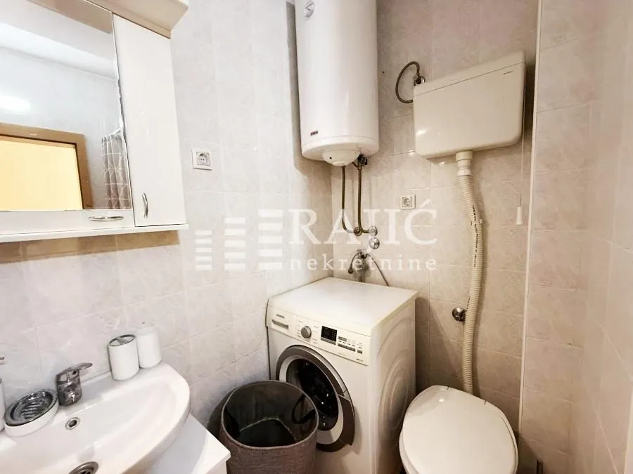 Smaller bathroom with sanitary facilities, a water heater, and a washing machine.