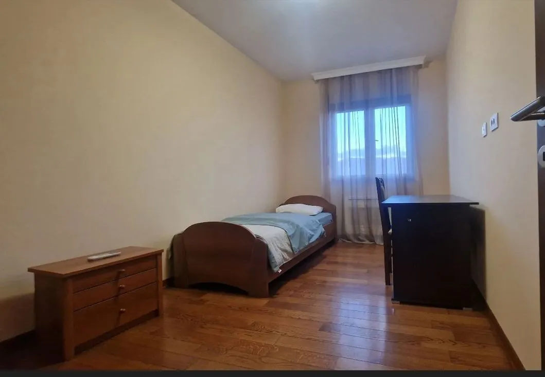 A simple bedroom with a single bed and a desk.