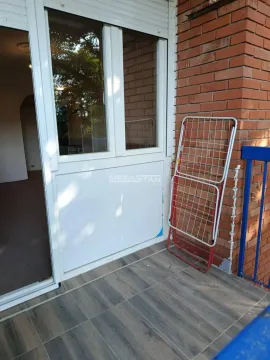 Pogled na popločanu terasu sa balkonskim vratima i sklopivom sušilicom za veš. - image 11