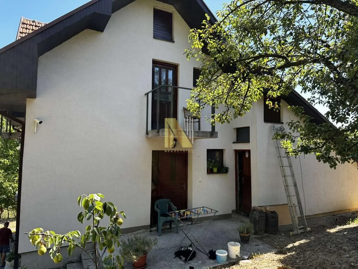 Pogled na spoljašnjost kuće sa dvorištem i balkonom.