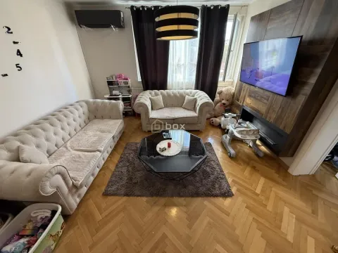 Nameštena dnevna soba sa garniturom, stočićem i televizorom na zidu. - image 2