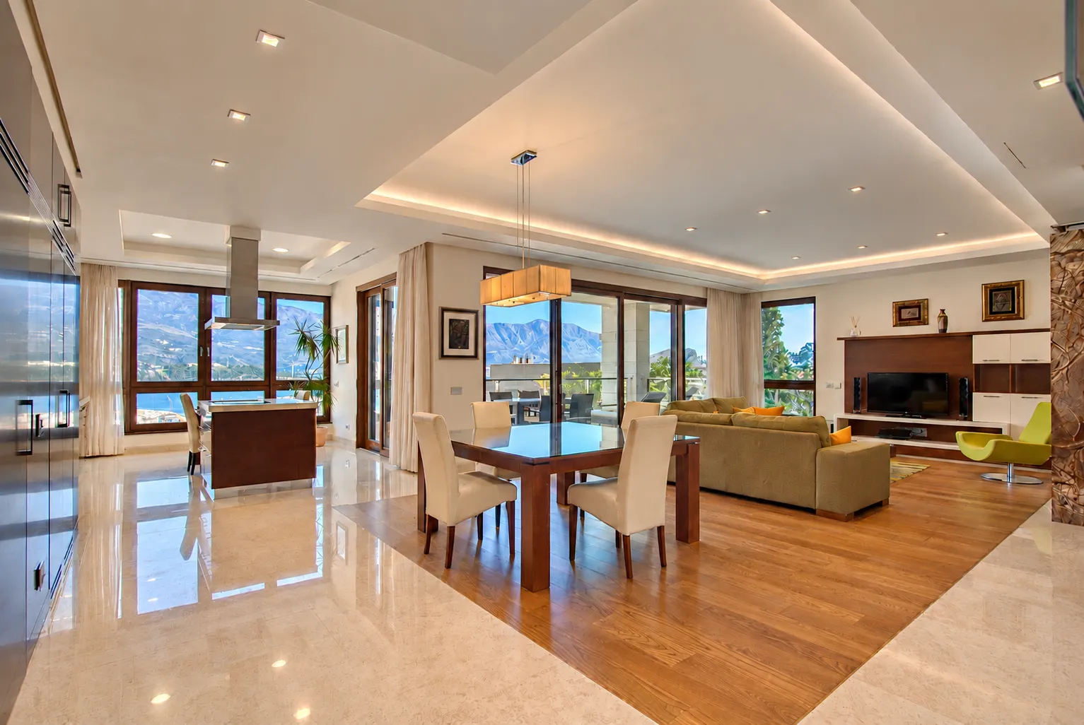 Spacious open-plan living room with dining area, kitchen, and mountain views.