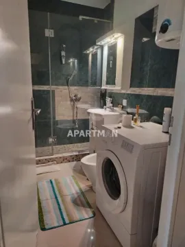 Bathroom equipped with a shower cabin, washbasin, and washing machine. - image 7