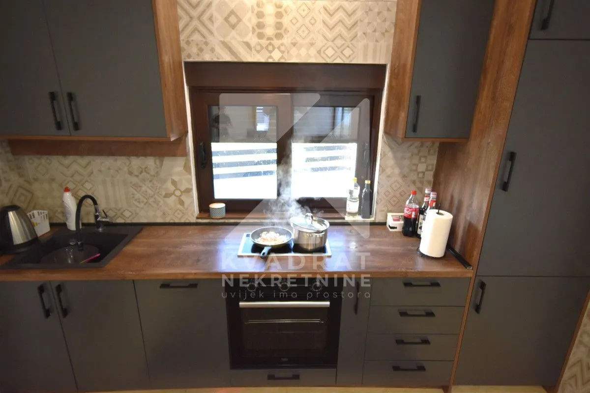 Modern kitchen with a wooden countertop, dark cabinets, and a built-in oven.