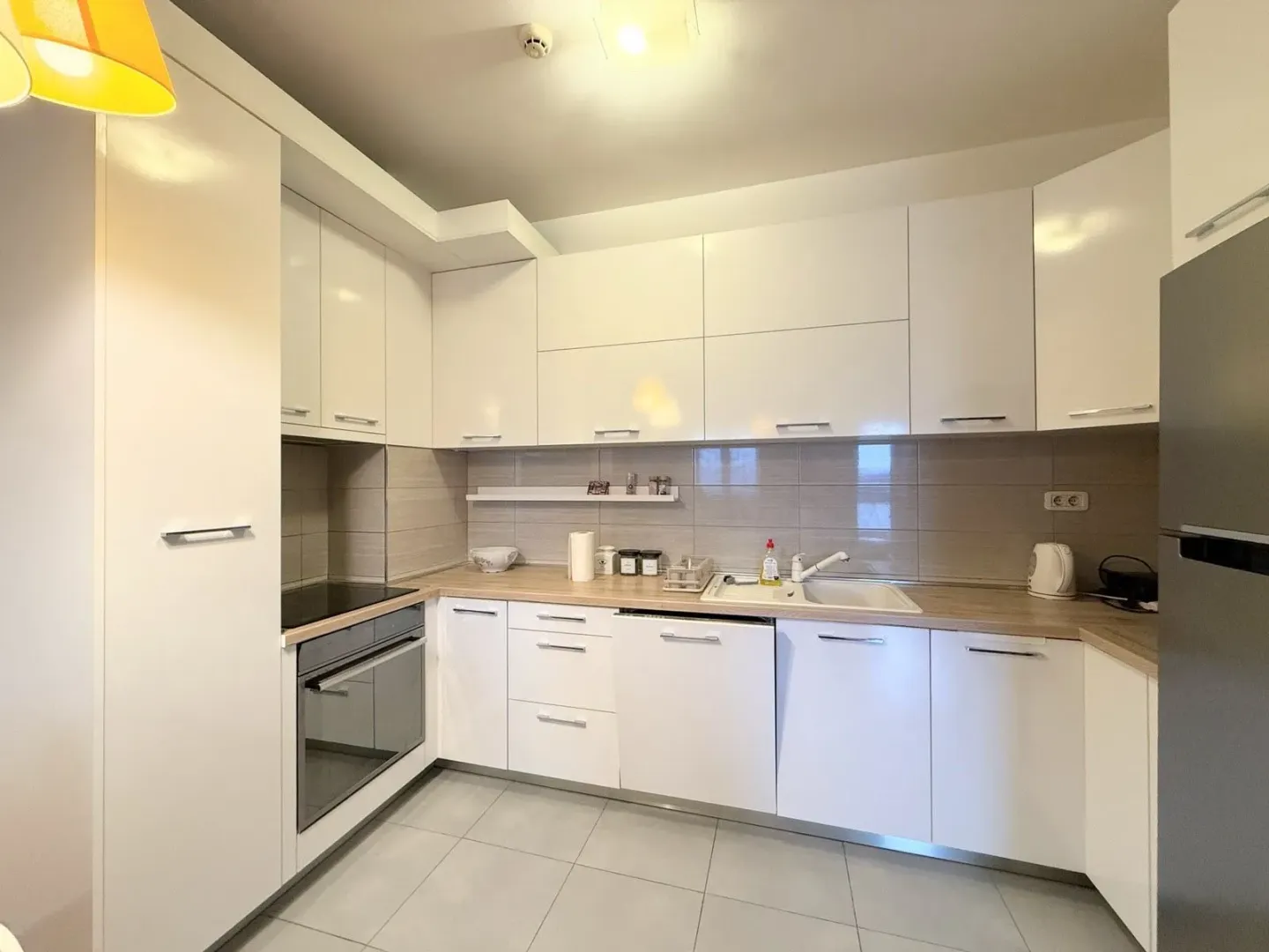 Modern white kitchen with built-in appliances and a wood-grain countertop.