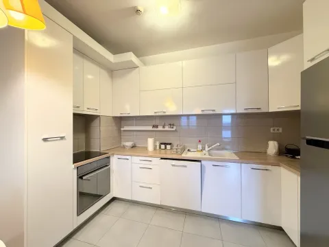 Modern white kitchen with built-in appliances and a wood-grain countertop. - image 3