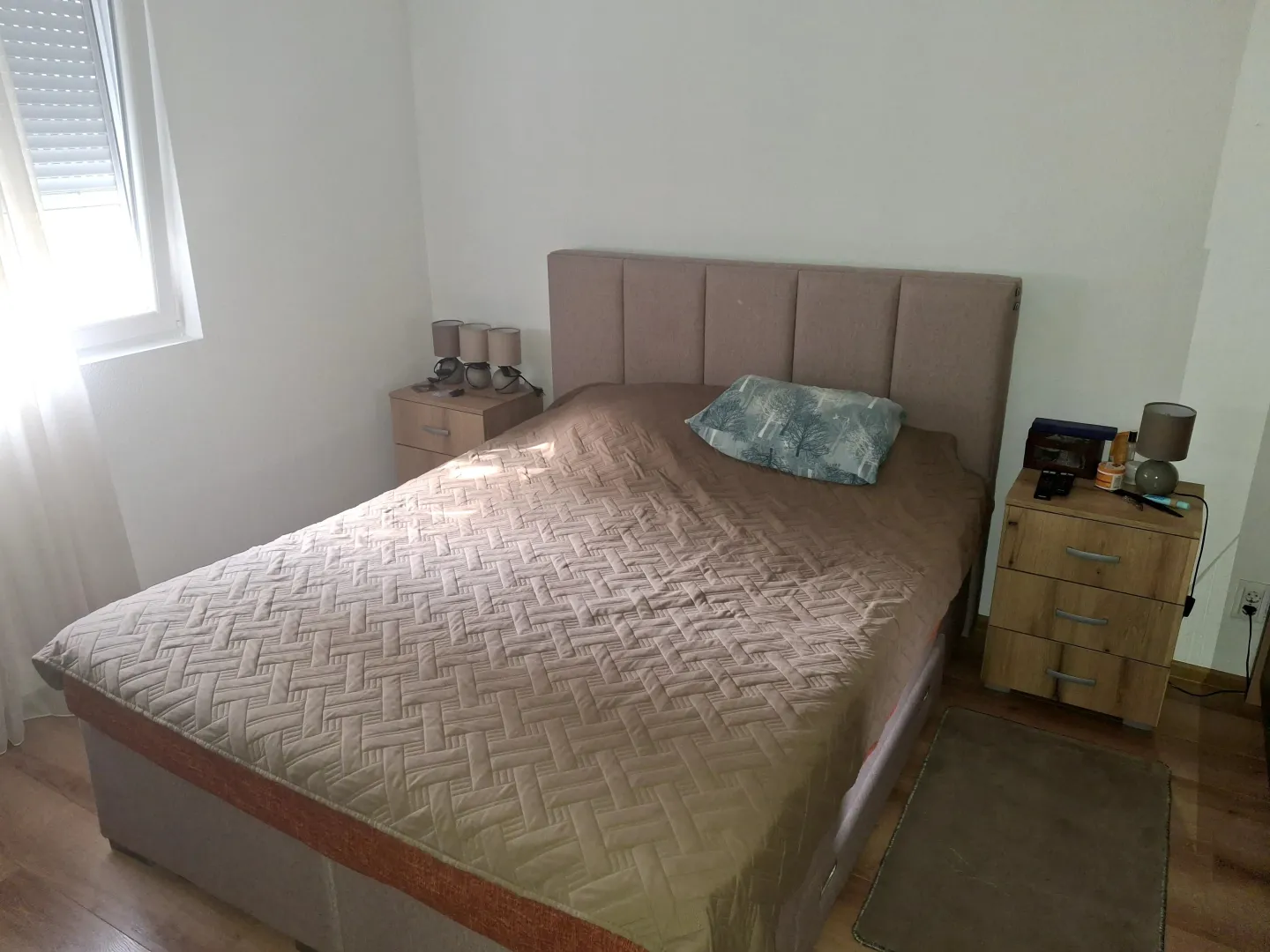 Namještena spavaća soba sa bračnim krevetom i noćnim stočićima.