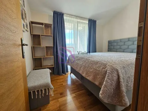 Furnished bedroom with a double bed, wooden shelving unit, and balcony doors. - image 8
