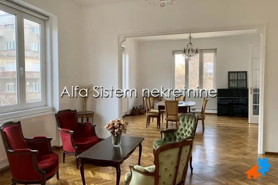 Prostrana dnevna soba sa stilskim nameštajem i drvenim podom.