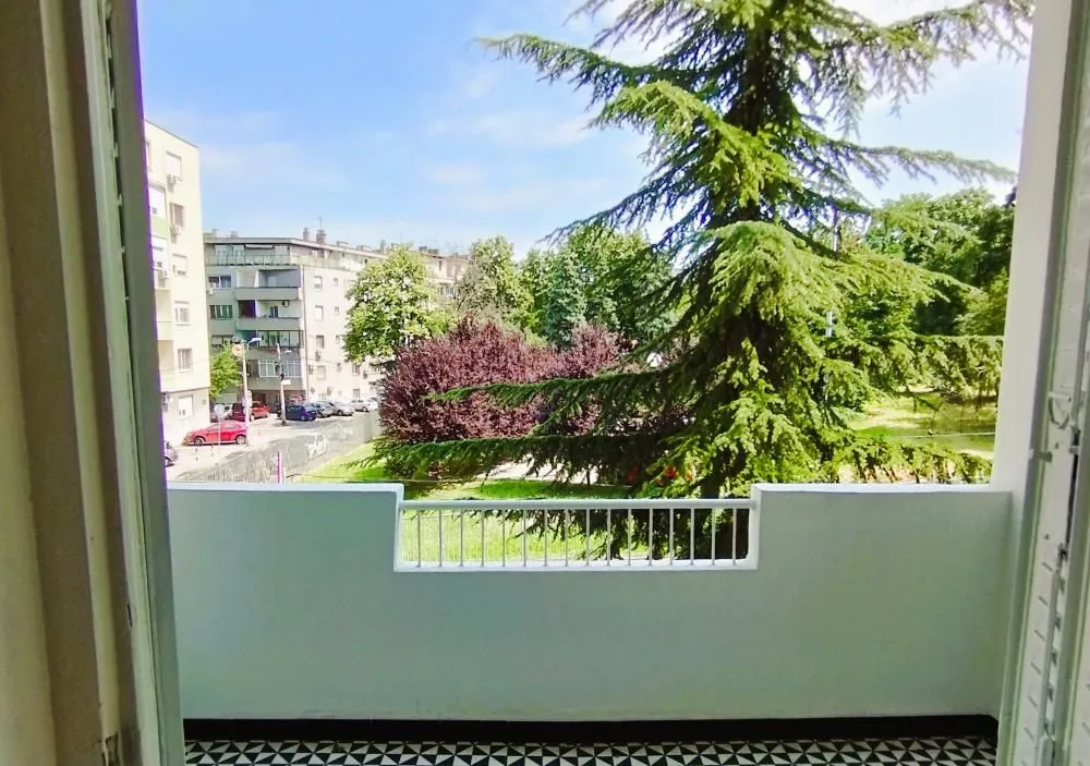 View from the balcony overlooking green areas and surrounding buildings.