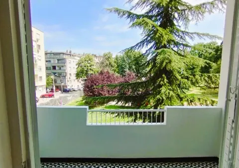 View from the balcony overlooking green areas and surrounding buildings. - image 13
