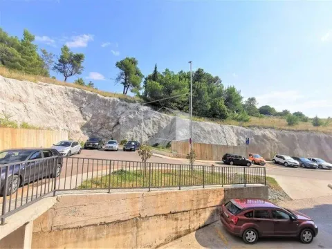 Outdoor area with parking spaces in front of a rocky hill. - image 14