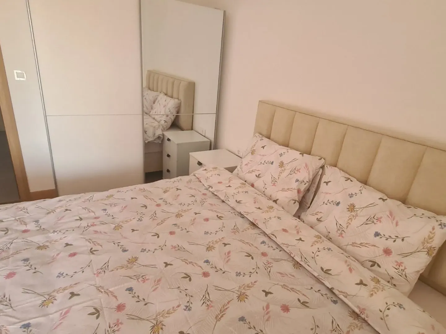 Furnished bedroom with a double bed and a mirrored wardrobe.