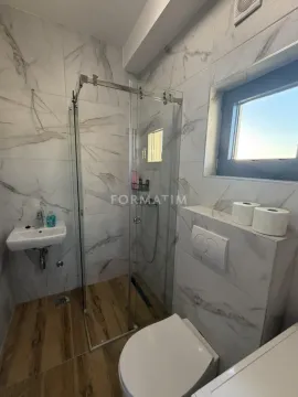 Modern bathroom with a walk-in shower and marble-effect tiles. - image 7