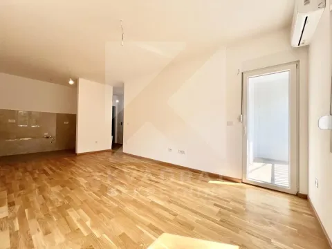 Prazna dnevna soba sa drvenim podom i izlazom na terasu. - image 2