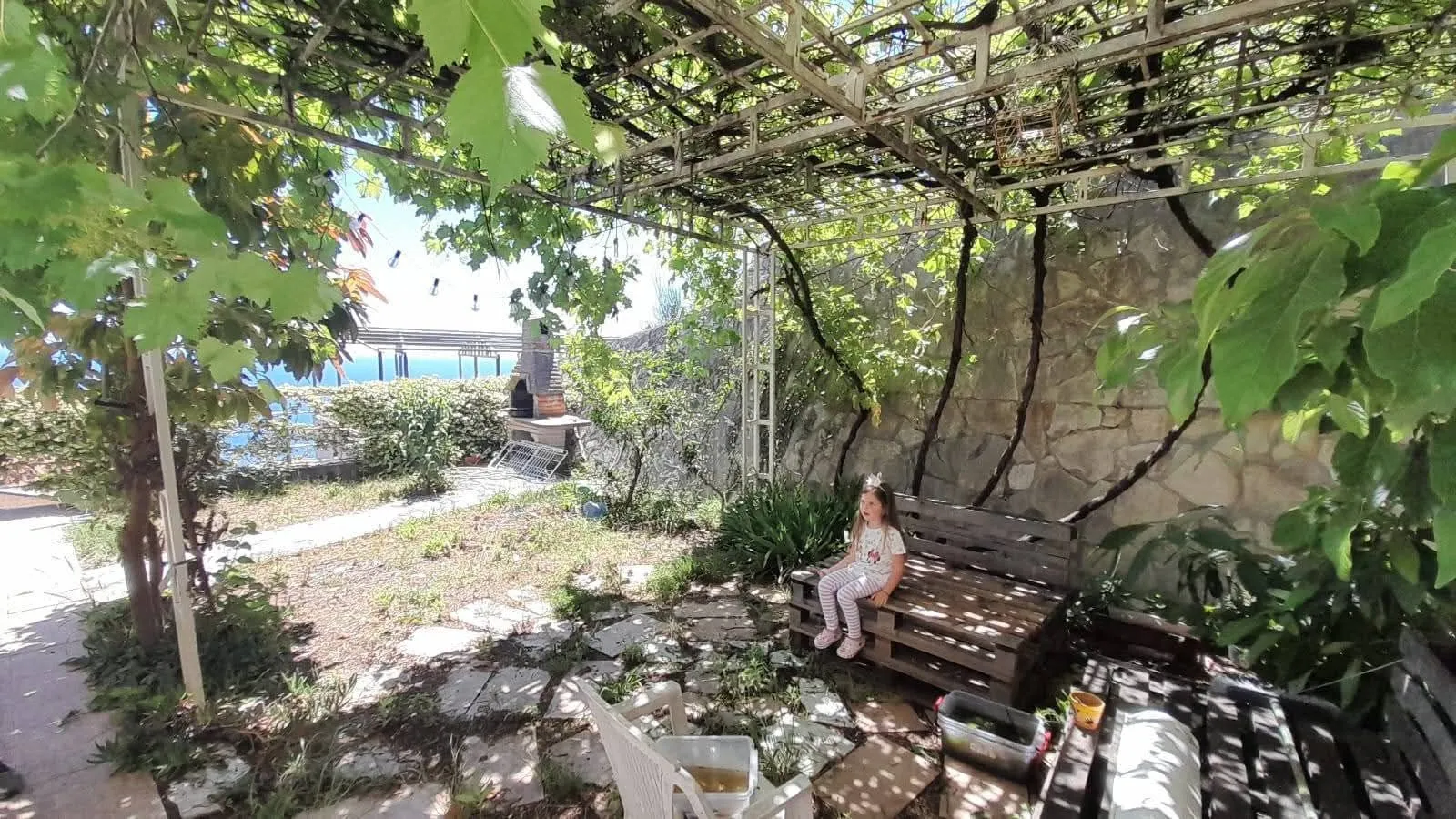 Dvorište sa natkrivenom sjenicom, klupom i kamenim roštiljem.