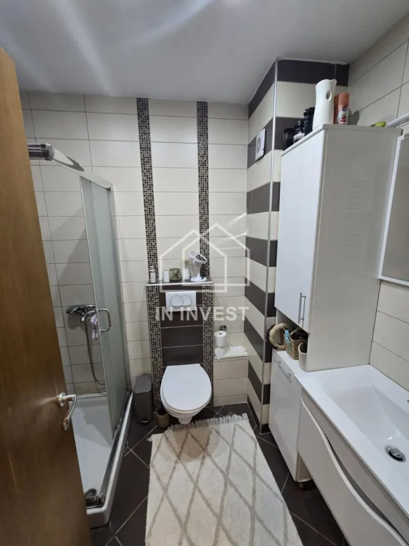 Kupatilo opremljeno tuš kabinom, WC šoljom i umivaonikom sa ormarićem.