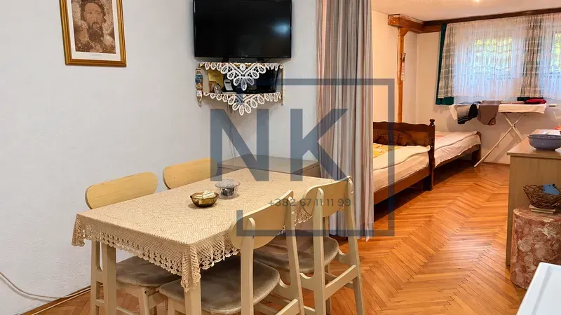 Living room with a dining table and a bed in the background.