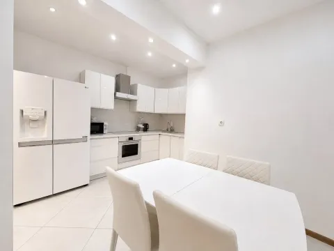 Modern white kitchen with a dining area and built-in appliances. - image 10