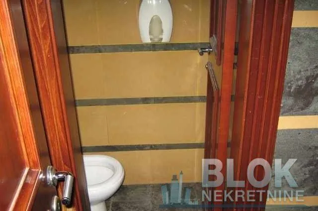Smaller bathroom with a toilet and brown ceramic tiles.