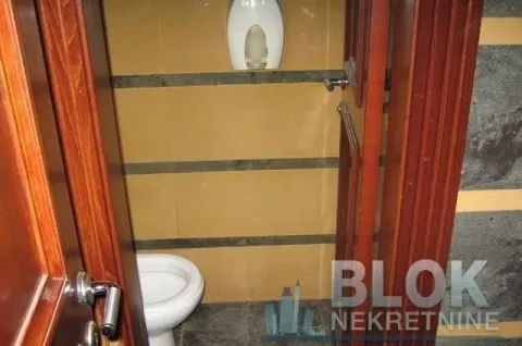 Smaller bathroom with a toilet and brown ceramic tiles. - image 8