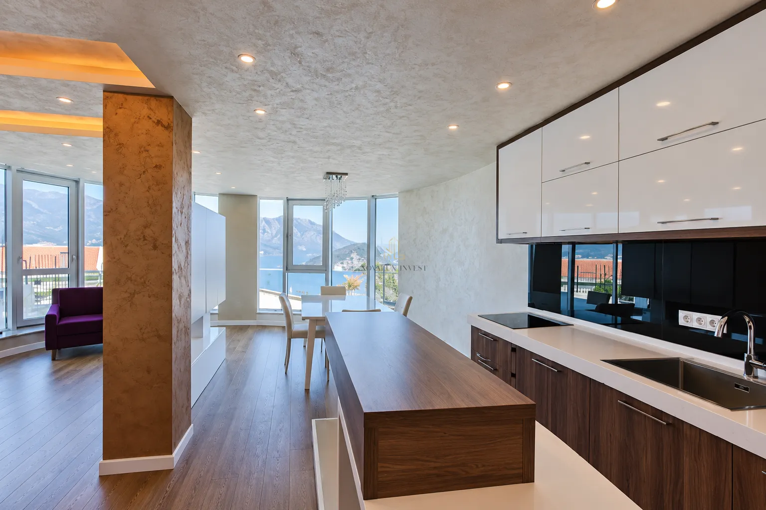 Modern kitchen with a breakfast bar and dining area, featuring sea views through large windows.