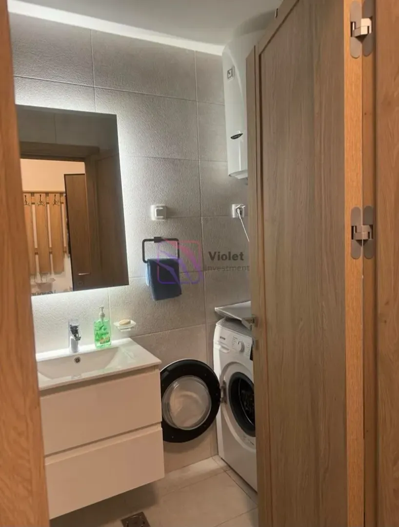 View of a small bathroom with a washbasin and a washing machine.