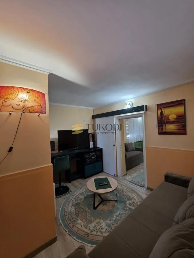 Smaller living room with a sofa, coffee table and television.