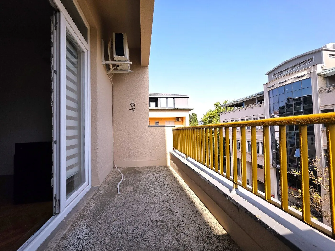 Balcony with a yellow railing and a view of surrounding buildings.