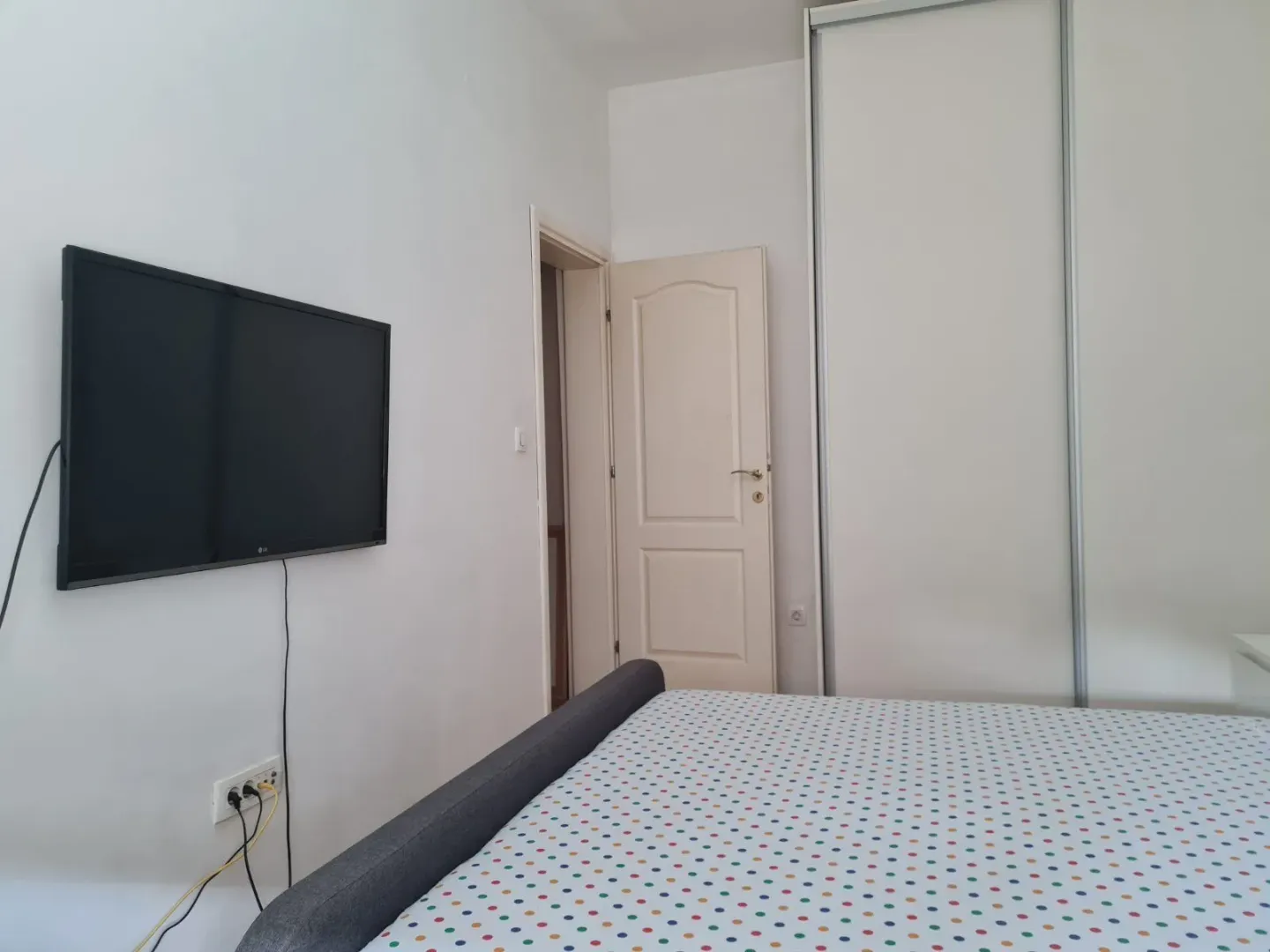 Bright bedroom with a built-in wardrobe and a wall-mounted TV.