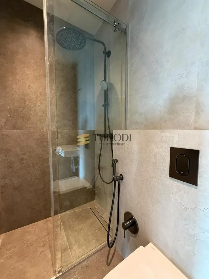 Moderno kupatilo sa tuš kabinom i ugradnom sanitarijom.