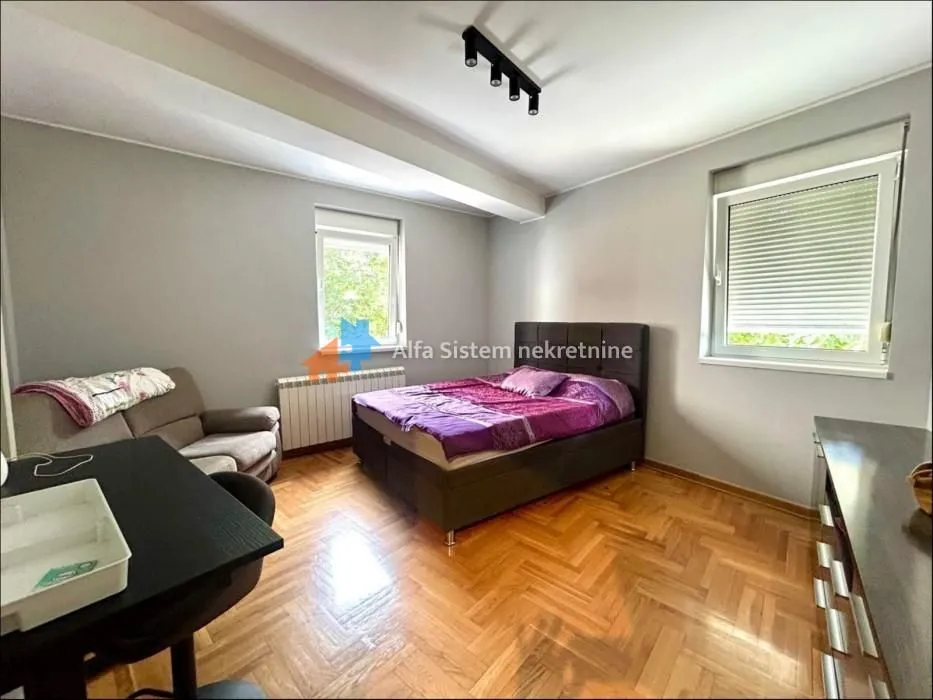 Furnished bedroom with a double bed, desk, and a two-seater sofa.